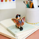 Calico cat with butterfly wings and strawberry sweater
