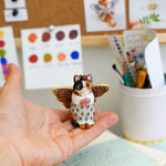 Calico cat with butterfly wings and strawberry sweater