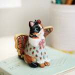Calico cat with butterfly wings and strawberry sweater