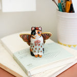 Calico cat with butterfly wings and strawberry sweater