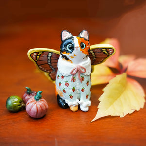 Calico cat with butterfly wings and strawberry sweater